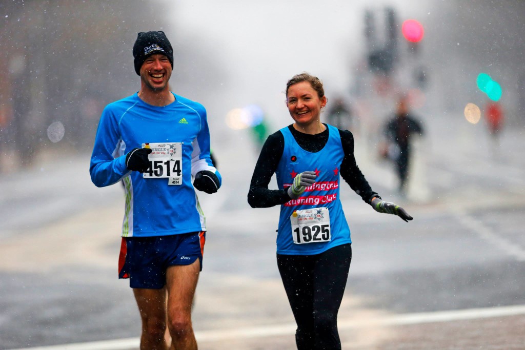 Drew Killian must have been apologizing to Rachel Clattenburg for not wearing his club singlet; perhaps he wants to upgrade from red-on-white to pink-on-turquoise? Regardless, singlet designer and Grand Prix contender, Rachel, proudly wears her own work to the Jingle All the Way 8K. Photo by Swim Bike Run Photography/Brian W. Knight